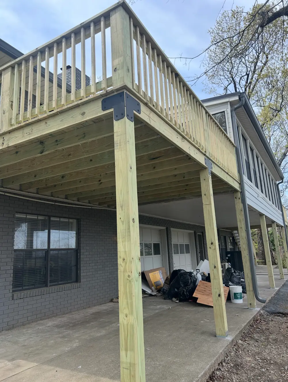 New elevated pressure-treated deck with balusters on a grey brick house