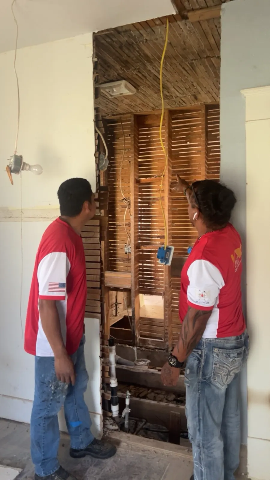 Two JMI crew members inspecting a wall opened down to the lath and wiring